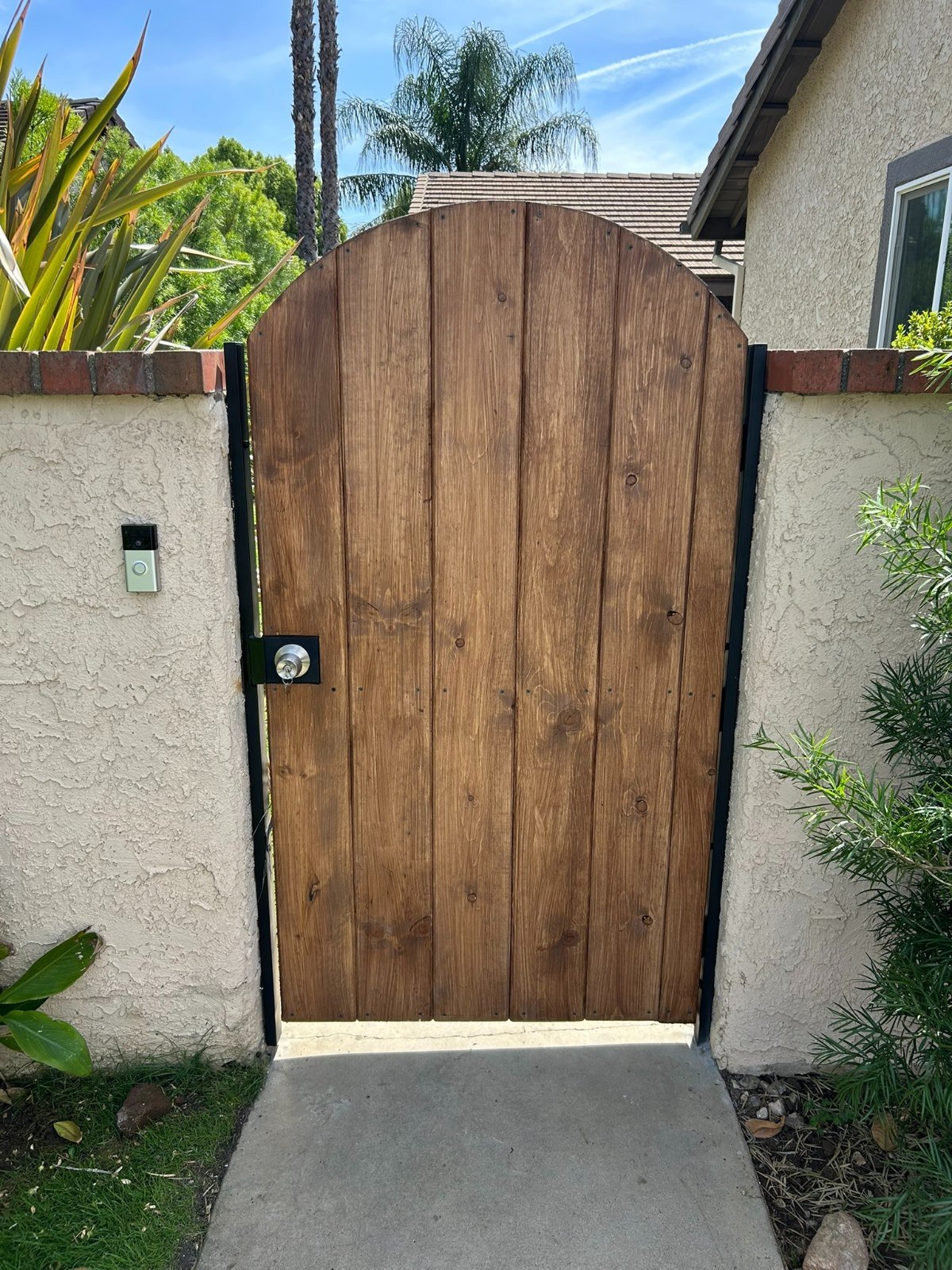 Arched wood front walkway gate with a black steel frame in La Verne