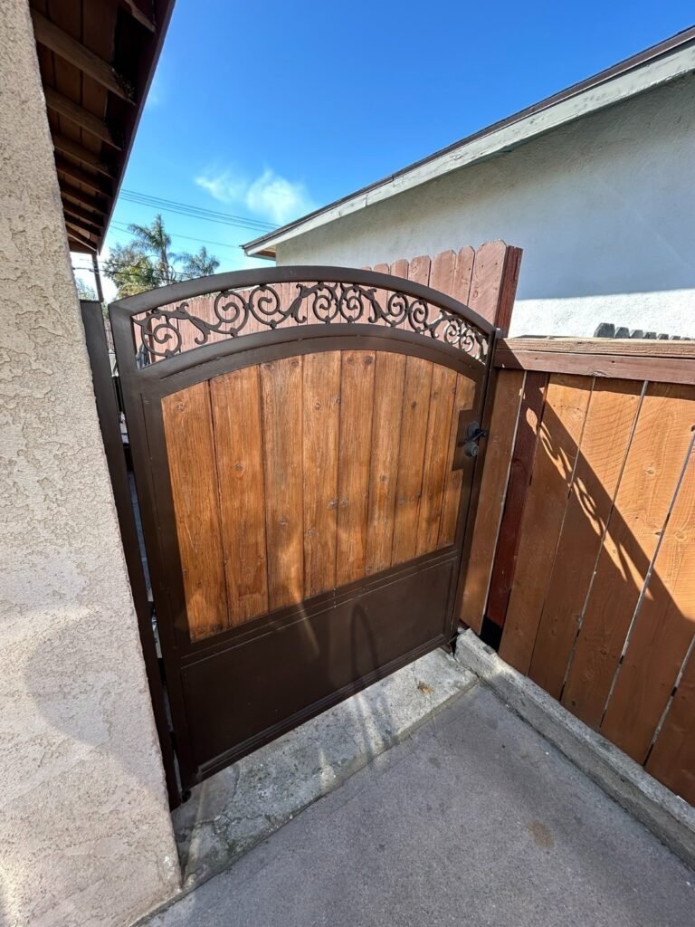 Arched steel-framed wood side gate with a wrought iron scroll top in Whittier