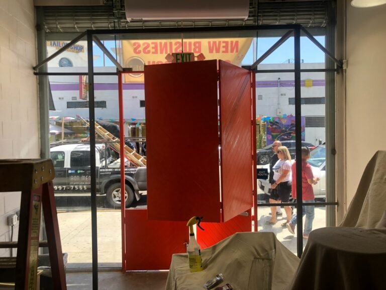 Custom red-painted steel storefront entry frame and doors fabricated for a new business in Downey