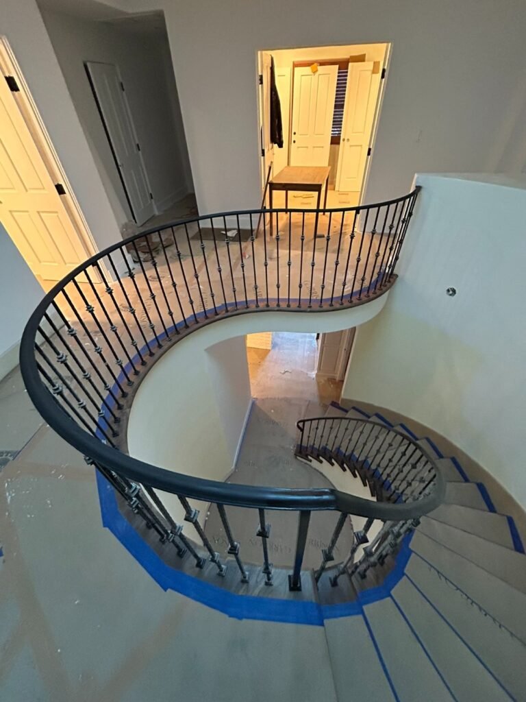 Custom curved wrought iron staircase railing with round balusters in a Bel Air home