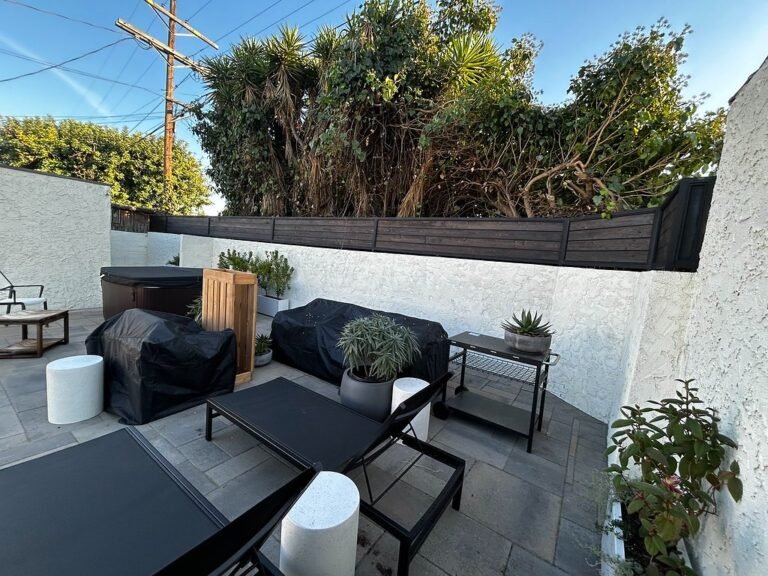 Backyard patio with a black steel privacy screen along the top of the wall