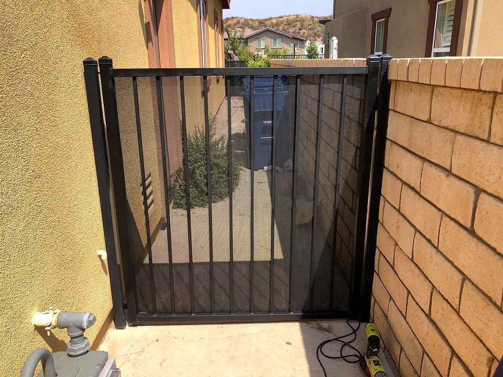 Black iron picket side gate between stucco and block walls
