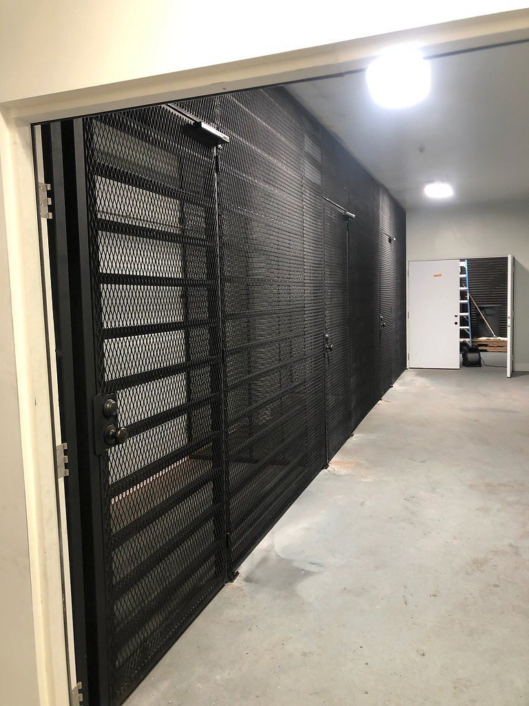 Black steel security cage with mesh doors in a hallway