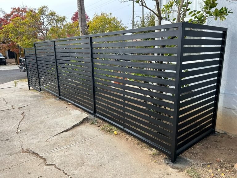 Black horizontal slat steel fence along a sidewalk in Westchester