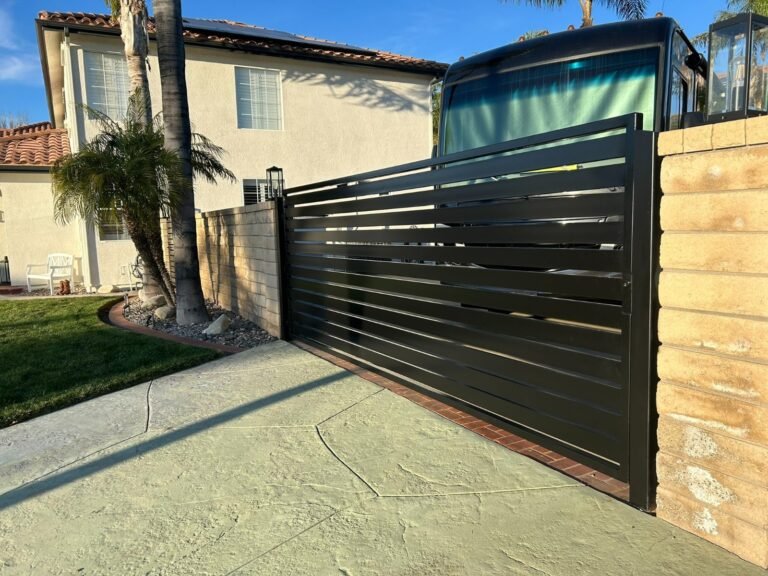 Black horizontal slat steel sliding driveway gate beside a block wall in Stevenson Ranch