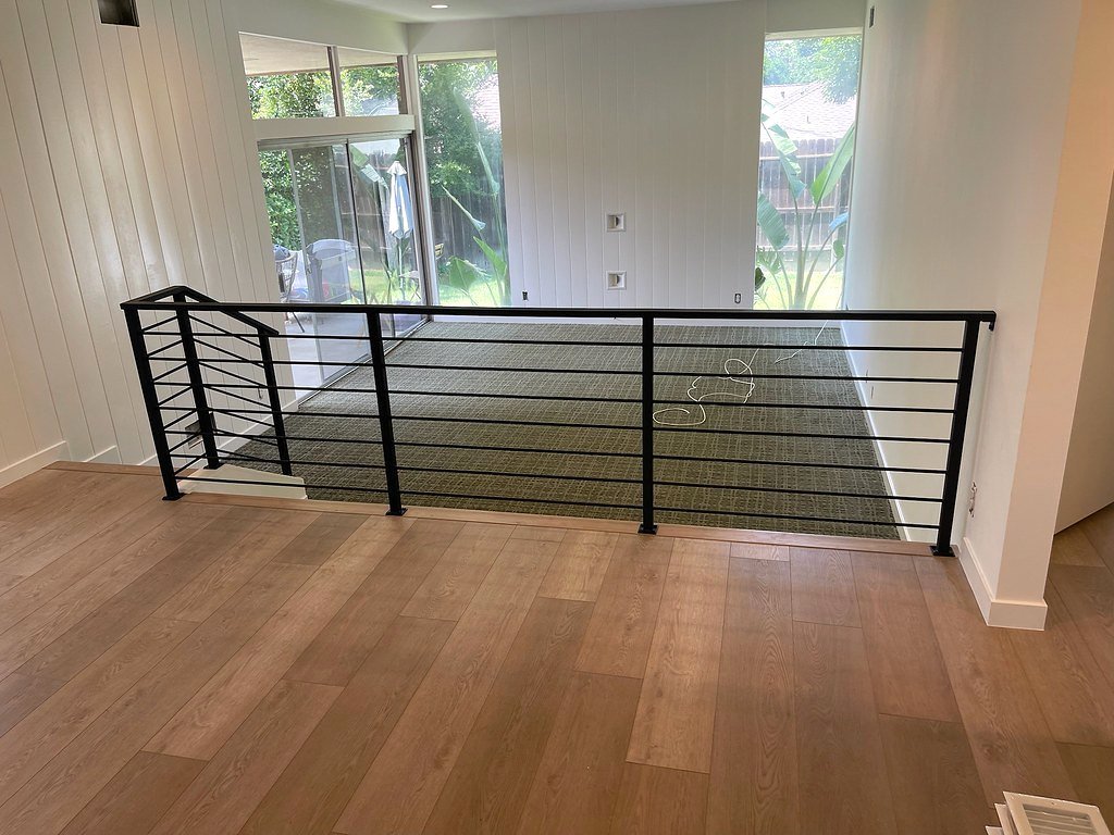 Modern black iron railing with horizontal bars around an open loft with wood floors