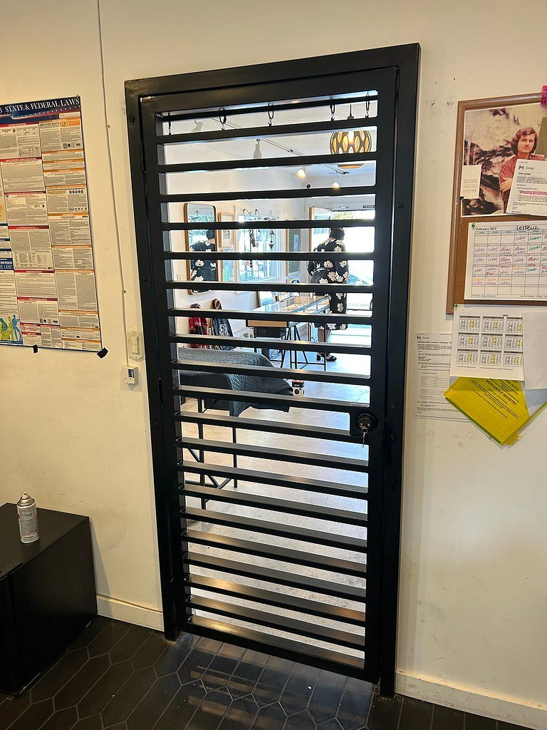 Black iron security door with horizontal bars inside an office