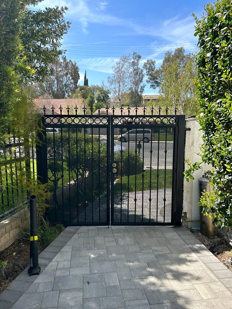 Black iron double driveway gate over a paver driveway