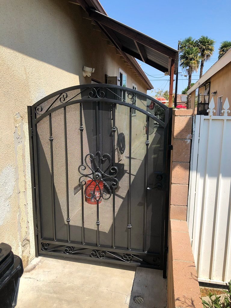 Arched iron security screen door with decorative scroll accent