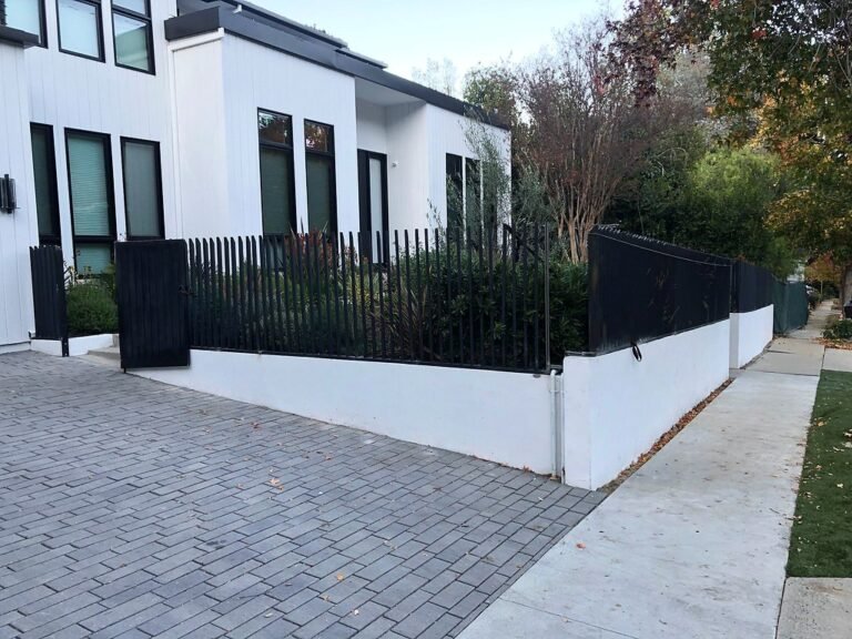 Modern black iron picket fence on a white wall in front of a contemporary home