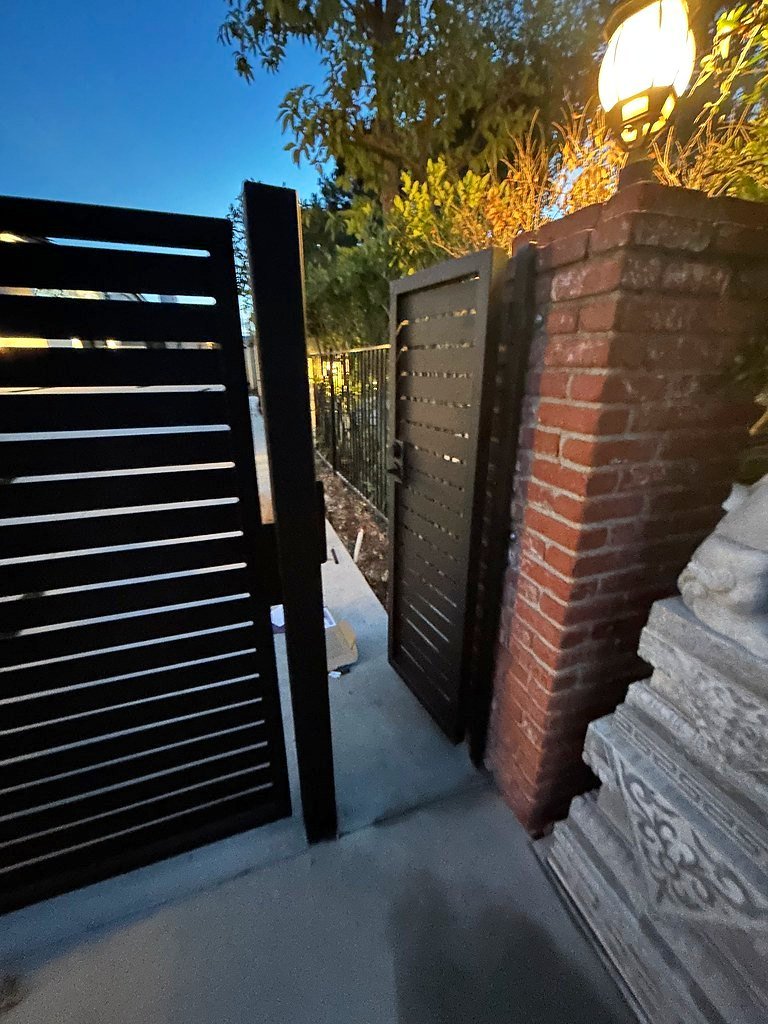 Horizontal slat iron gate beside a brick pillar