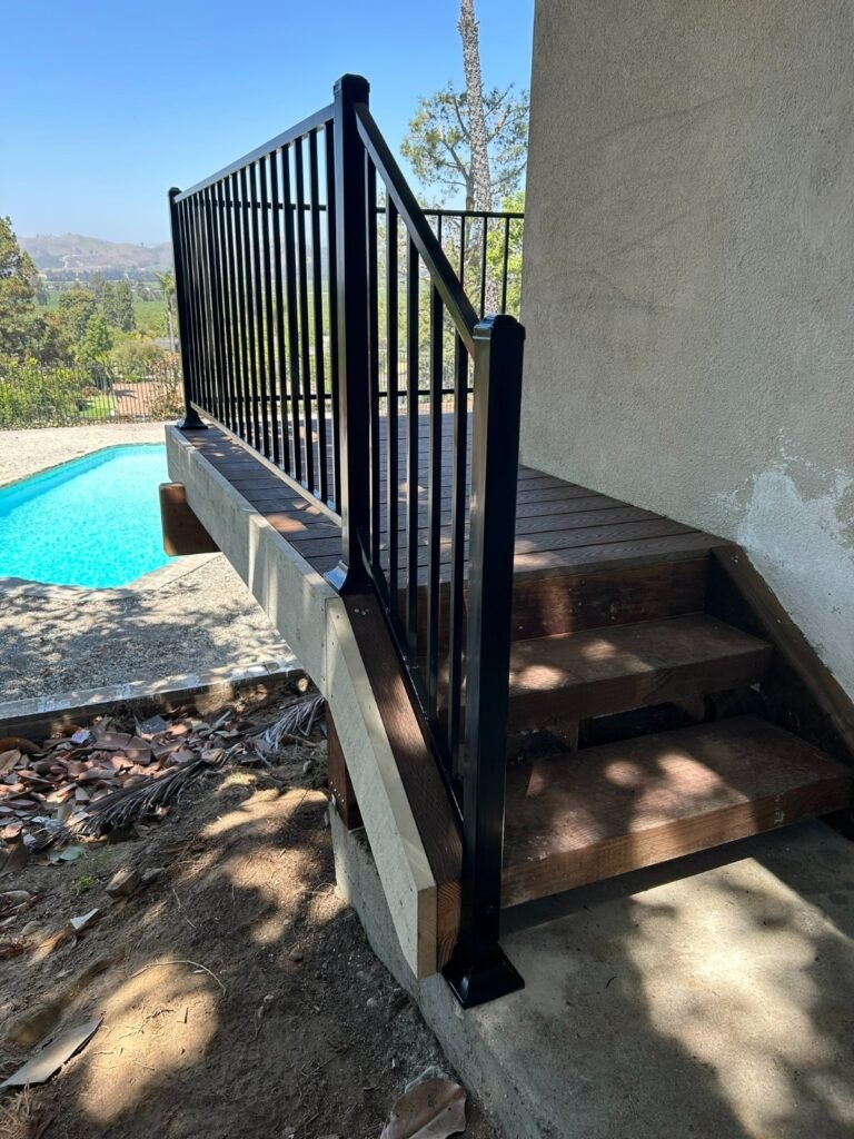 Black iron deck and stair railings overlooking a backyard pool in Castaic