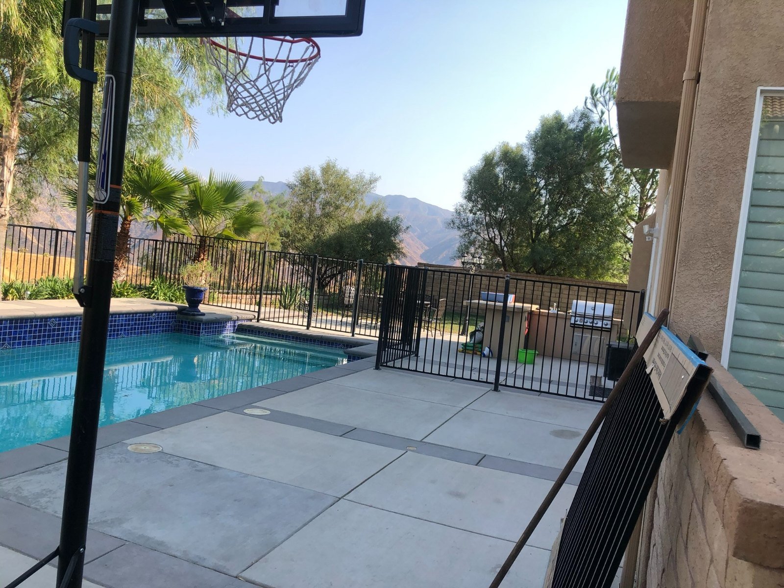 Black iron pool safety fence and self-closing gate around a backyard pool in Shadow Hills