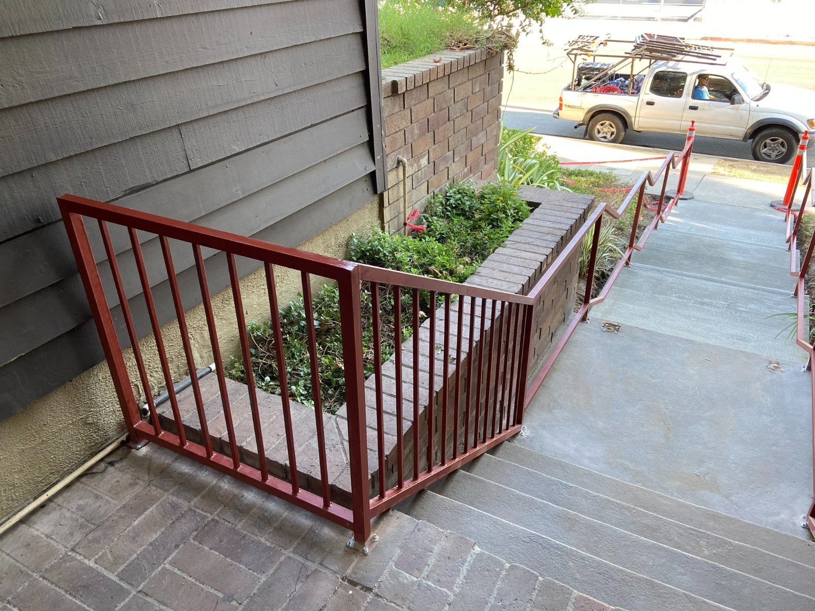 Red-painted steel stair railings along a front entry walkway in Monterey Park
