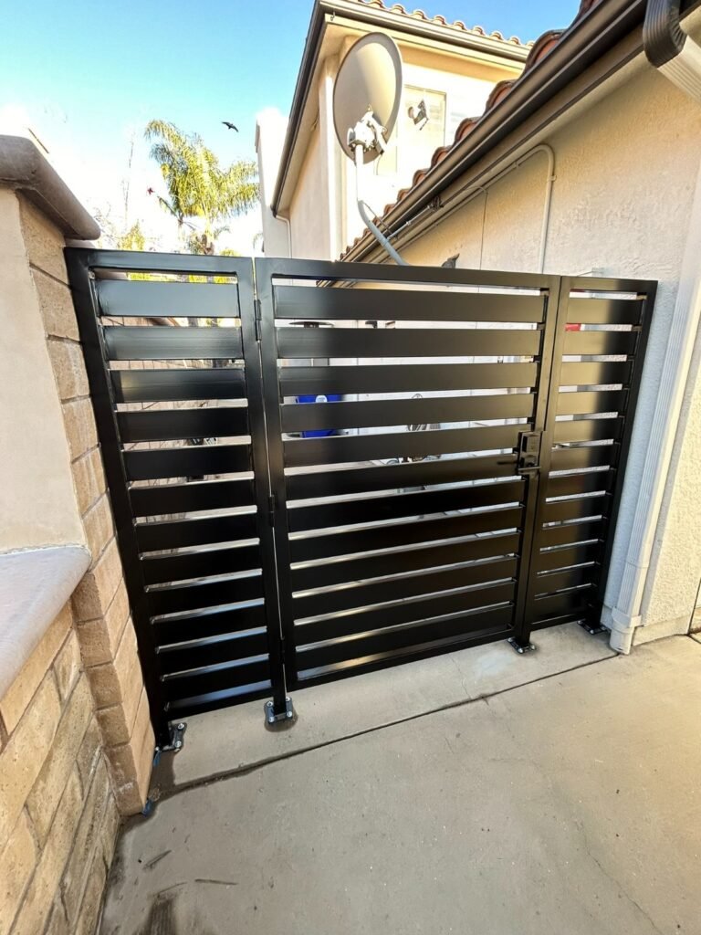 Black horizontal slat steel double side gate between a block wall and stucco house in Santa Clarita