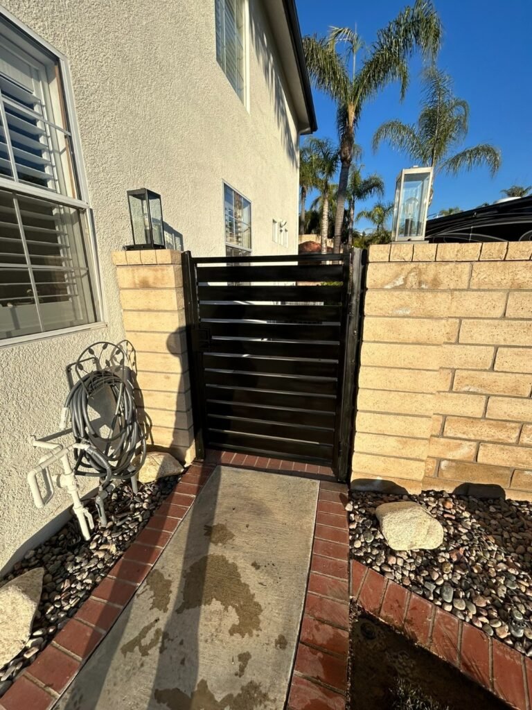 Black horizontal slat steel side gate between block walls in Saugus
