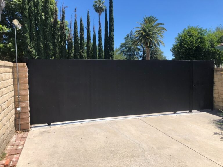 Solid black steel sliding driveway gate between block walls in Winnetka