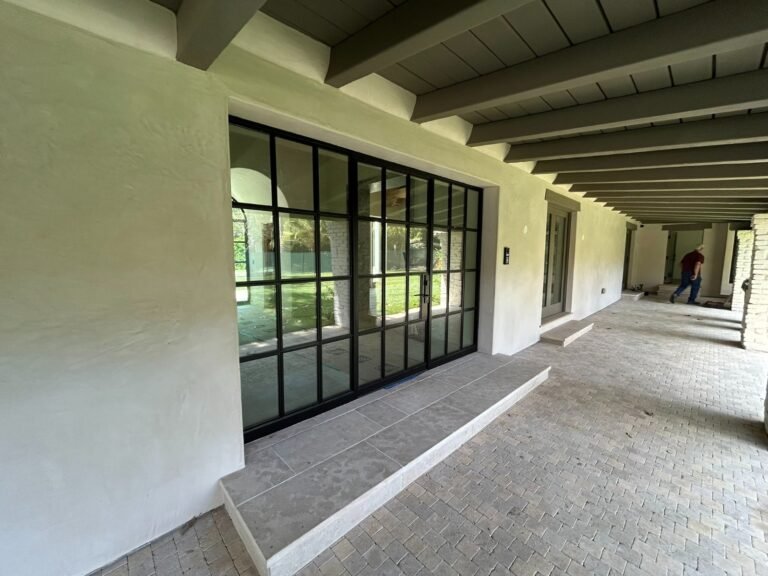 Black steel-frame windows and French doors along a covered patio in Brentwood