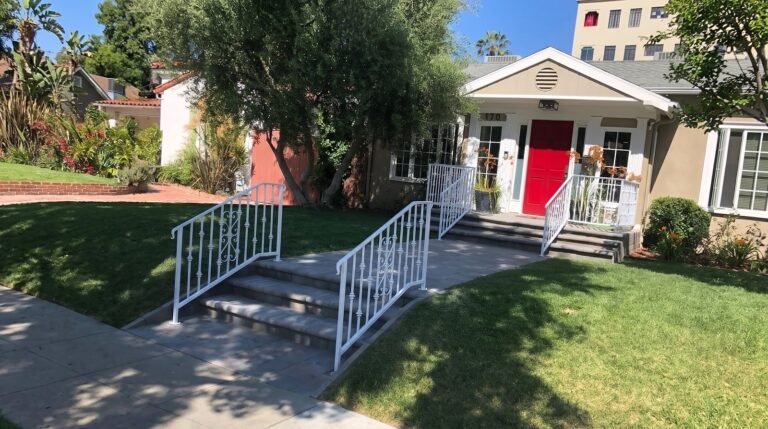 White wrought iron porch and step railings at a Pasadena home with a red front door