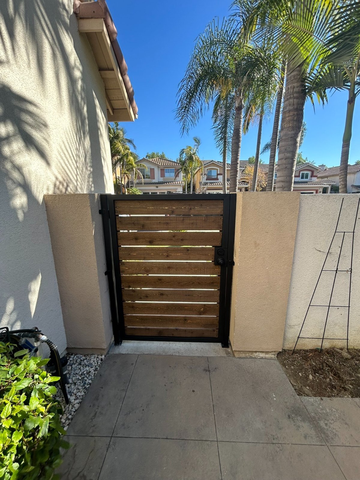Flat-top steel-framed side gate with wood infill between stucco pillars in Torrance
